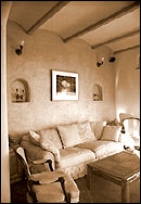 The inviting living room is oriented toward the south-facing windows. Above the couch are two of the many niches carved into the mud plaster walls.